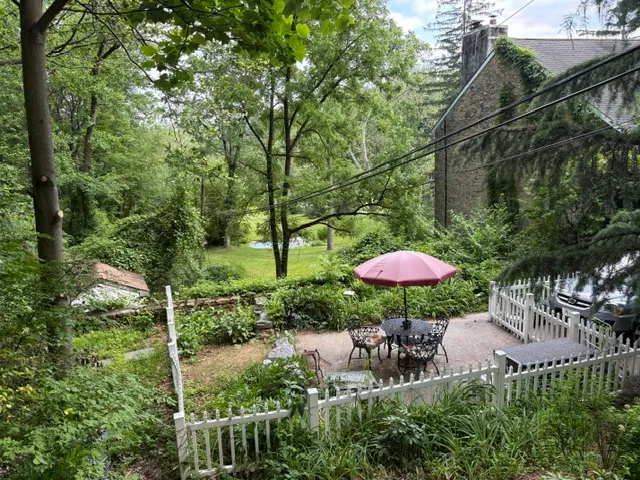 Garden patio with pink umbrella and stone cottage